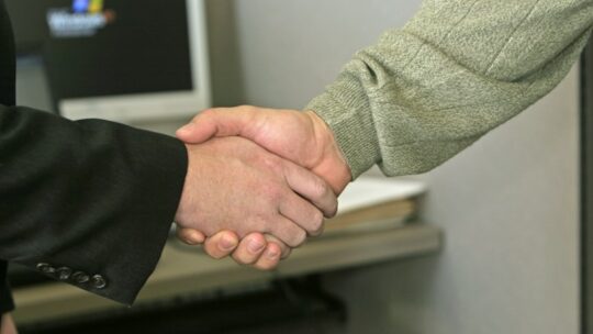 Professionals shaking hands after closing business acquisition
